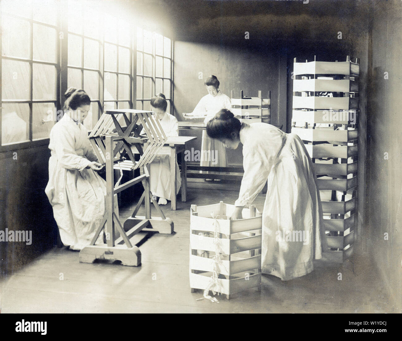 [ 1890s Japan - Sericultural School for Women ] —   Women in uniform working with silk in a sericultural school in 1898. Japan had a large number of these schools, many managed by the prefectural and county government, others private. Photographed by N. Iketa.  19th century vintage gelatin silver print. Stock Photo