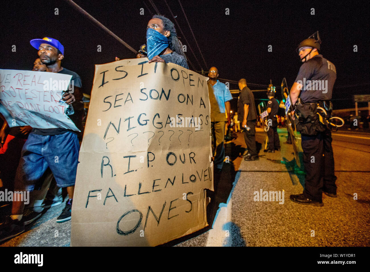 Police and protesters clash in the streets of Ferguson. Heavily armed police provoked many of the protesters as they swooped in, guns pointing, to  arrest deemed 'troublemakers' among the protesters in downtown Ferguson following the killing of unarmed Michael Brown (18). Stock Photo
