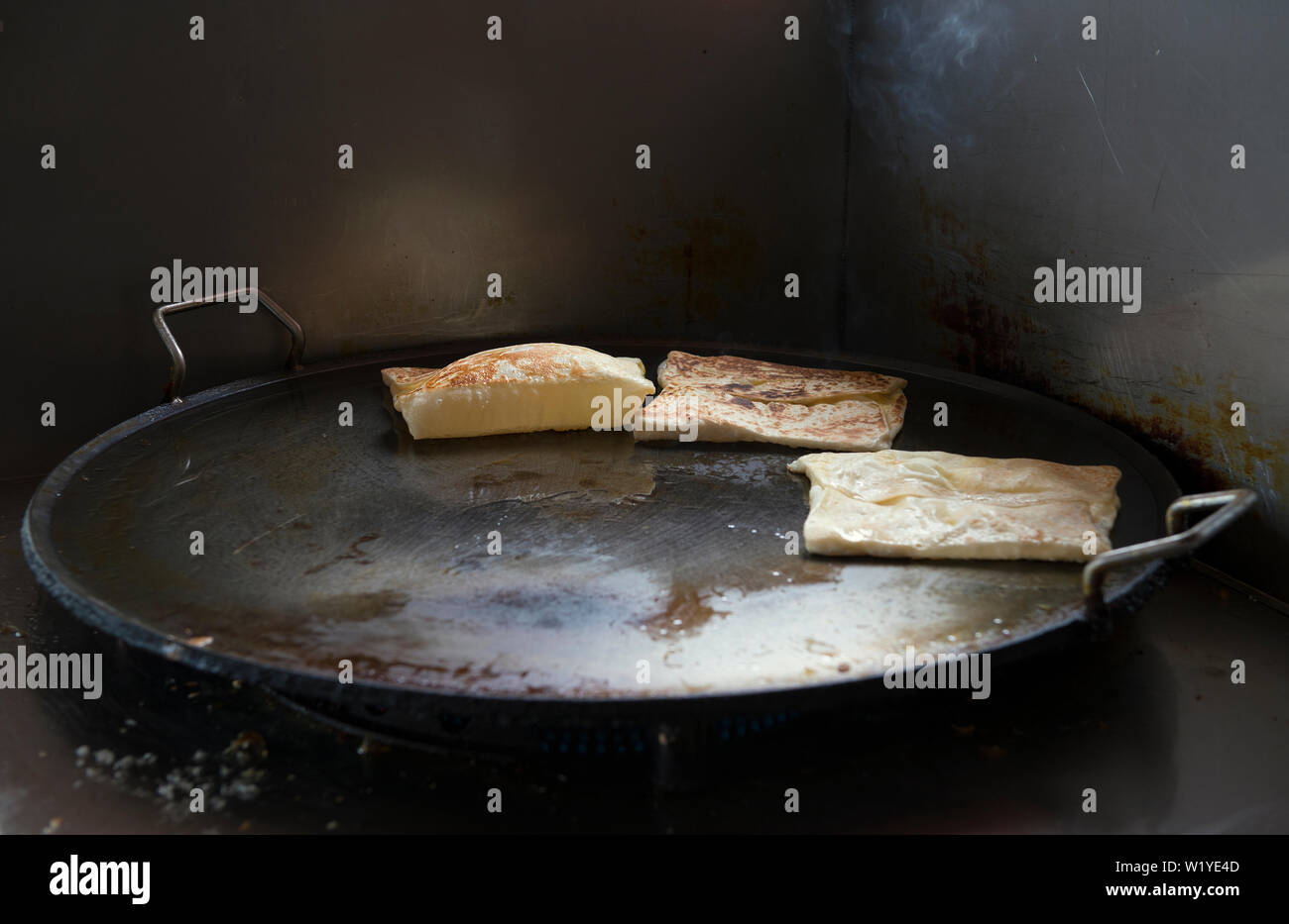 kuching, sarawak/malaysia - january 31, 2017: preparation of   roti canai in a pan outside a restaurant Stock Photo