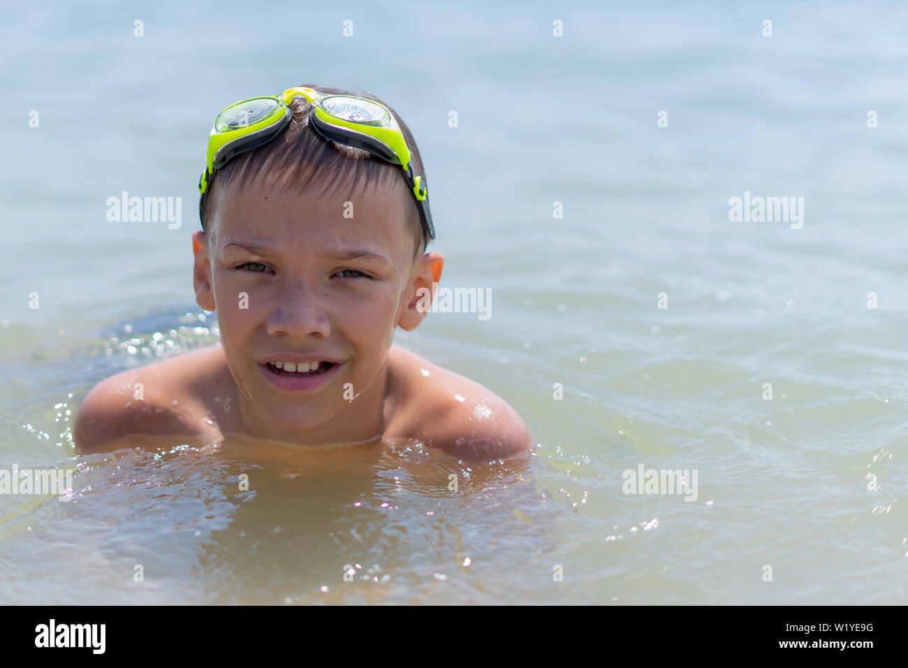 A boy of 10 years old is swimming in the sea on a clear sunny day Stock