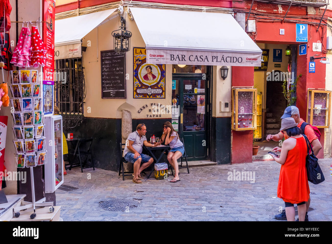 People at outdoor cafe in the Barrio de Santa Cruz or old Jewish Quarter of Seville Spain Stock Photo
