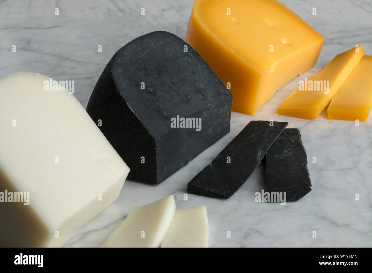 Pieces of Dutch white goat cheese, black lemon cheese and Gouda cheese for dessert Stock Photo