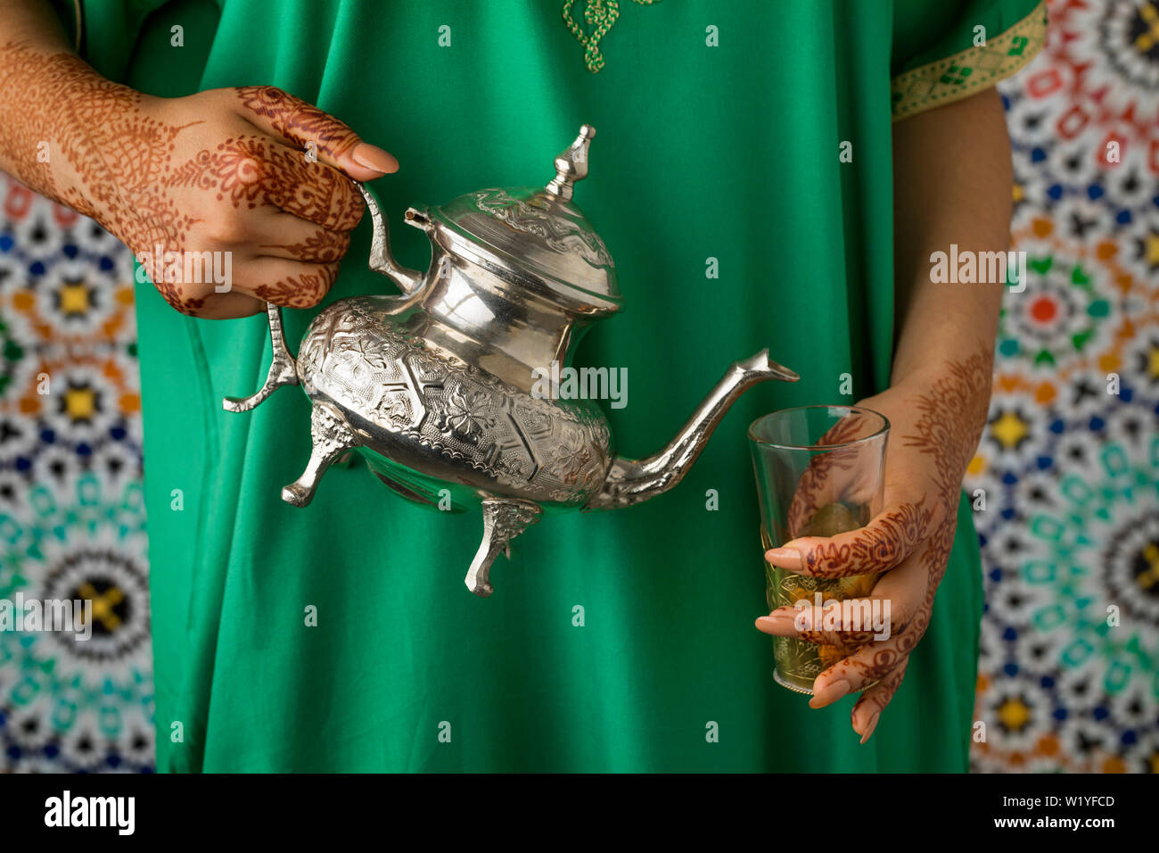 Moroccan woman with traditional henna painted hands pouring tea Stock