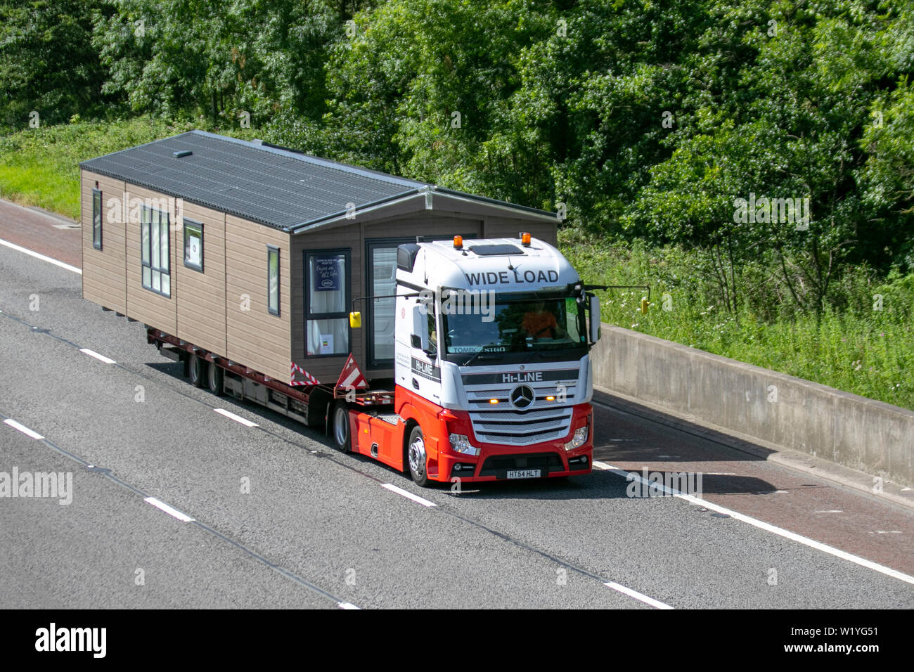 Merceders-Benz Hi-Line carrying static caravan on trailer; Commercial HGV vehicles travelling on the M6 at Lancaster. UK Stock Photo