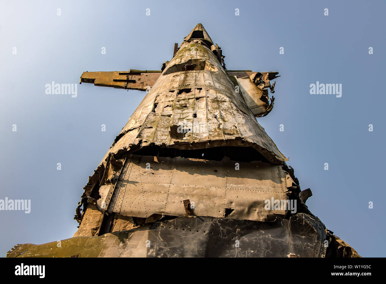The back of the wrecked air plane rises high to the blue sky. Part of the demolished airplane. Stock Photo
