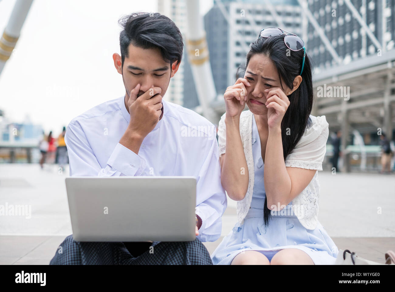 Couples are sit using laptop with sad about incident something in city Stock Photo