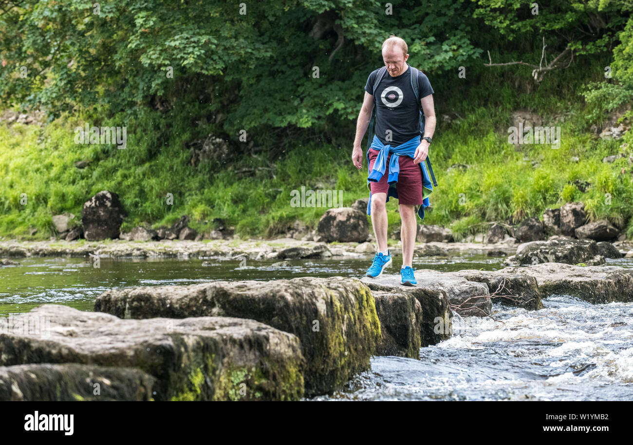 Walker on the stepping stones crossing the River Ure at Redmire, Yorkshire dales, UK. Stock Photo