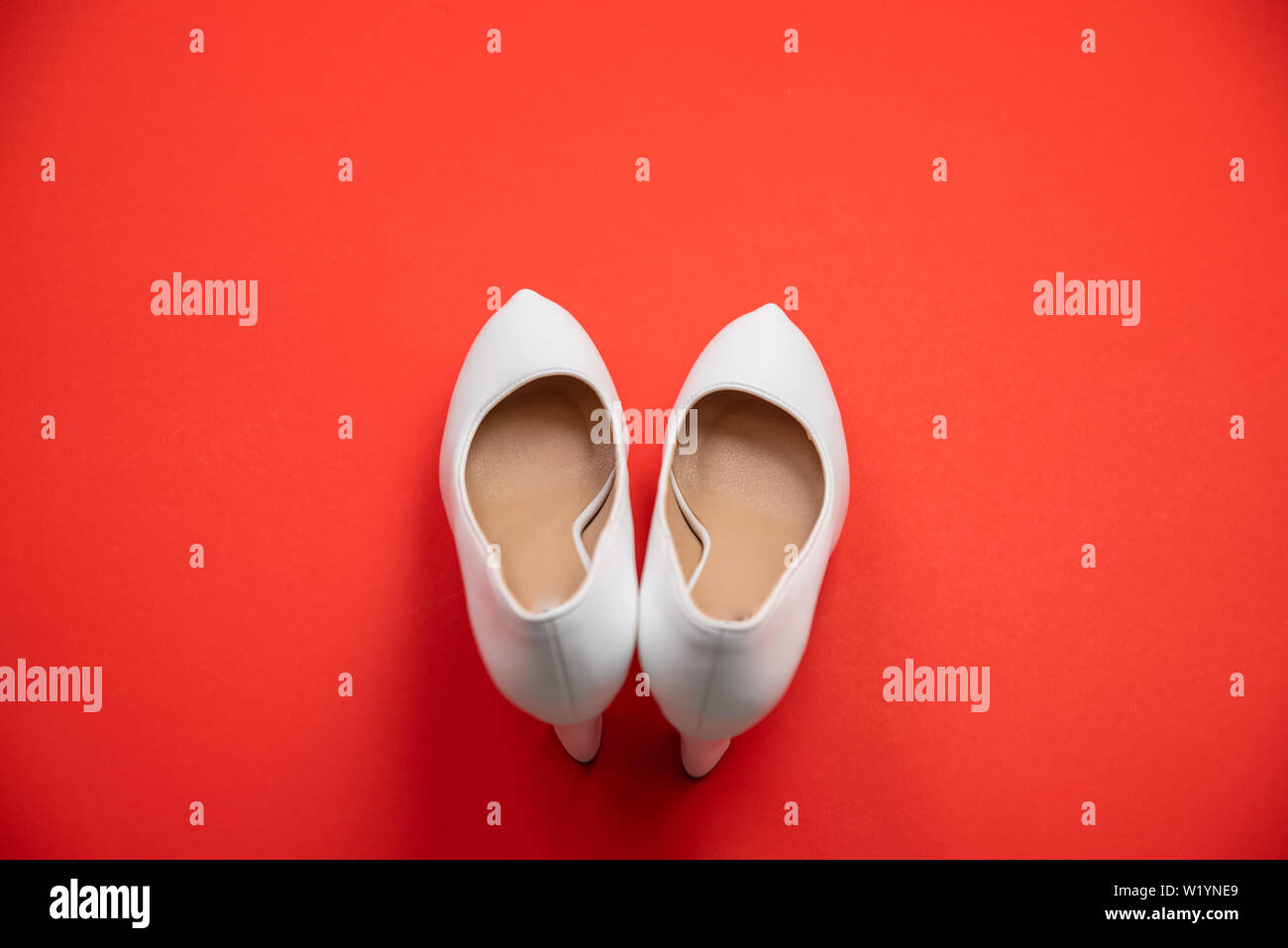 White high heeled shoes on red background - top view concept - blank empty room space for text or copy. Suitable for holidays like Valentine's or Chri Stock Photo