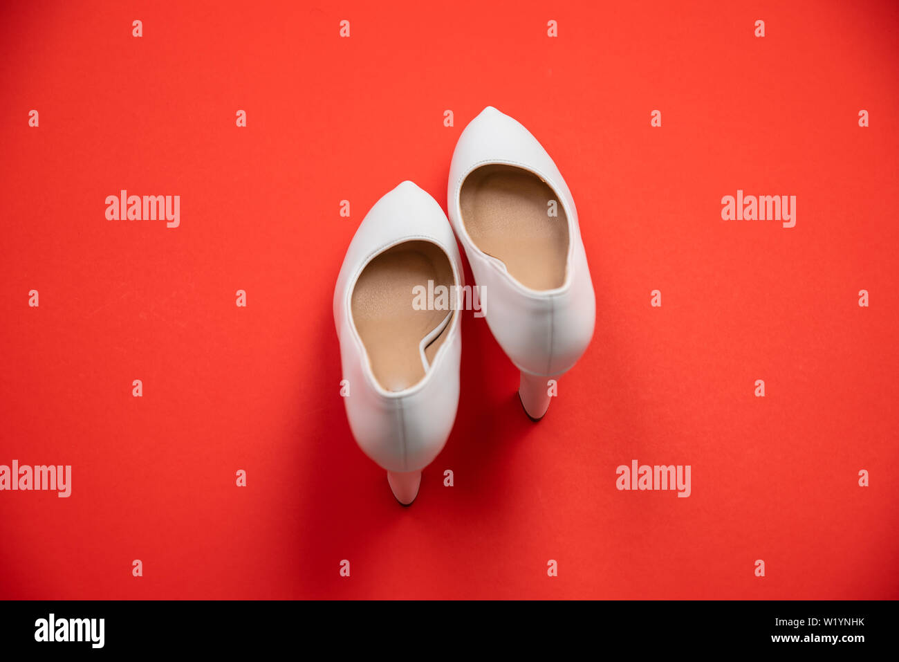 White high heeled shoes on red background - top view concept - blank empty room space for text or copy. Suitable for holidays like Valentine's or Chri Stock Photo