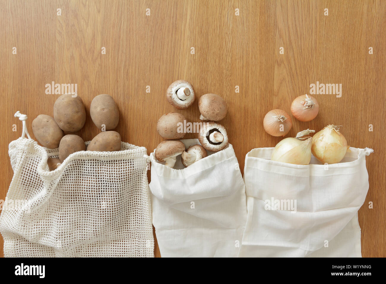 Thin and plastic free reusable grocery bags with fresh vegetables on wooden background, zero waste concept. Stock Photo