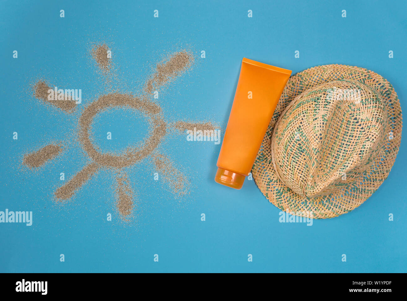 Sunscreens isolated on blue background. Sun drawn by the sand on blue background. Top view. Stock Photo