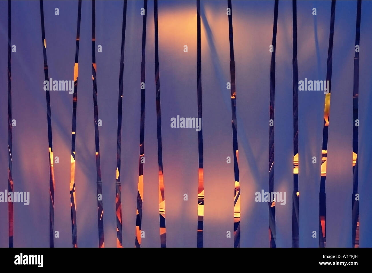 Frosted glass with vertical transparent strips, behind which there is a lighted hall, abstract interior background of yellow and purple colors. Stock Photo