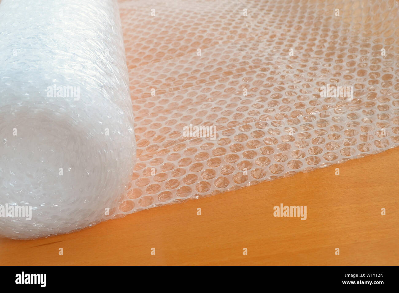 White transparent bubble wrap roll for packaging fragile items on an yellow background, view