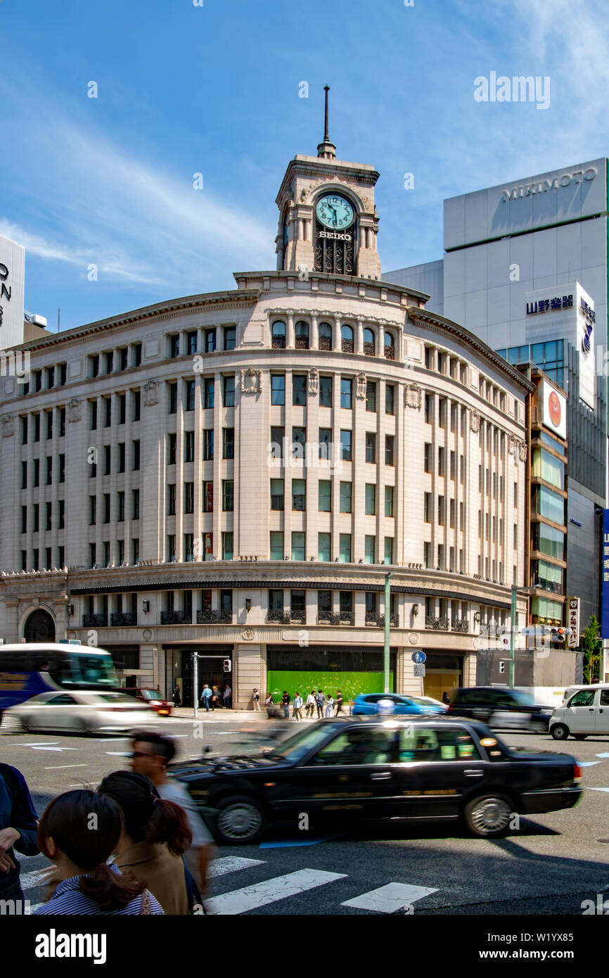 Traffic speeds across the Ginza Yonchome crossing in Tokyo, Japan, site of the Wako Department Store with its iconic clock tower Stock Photo