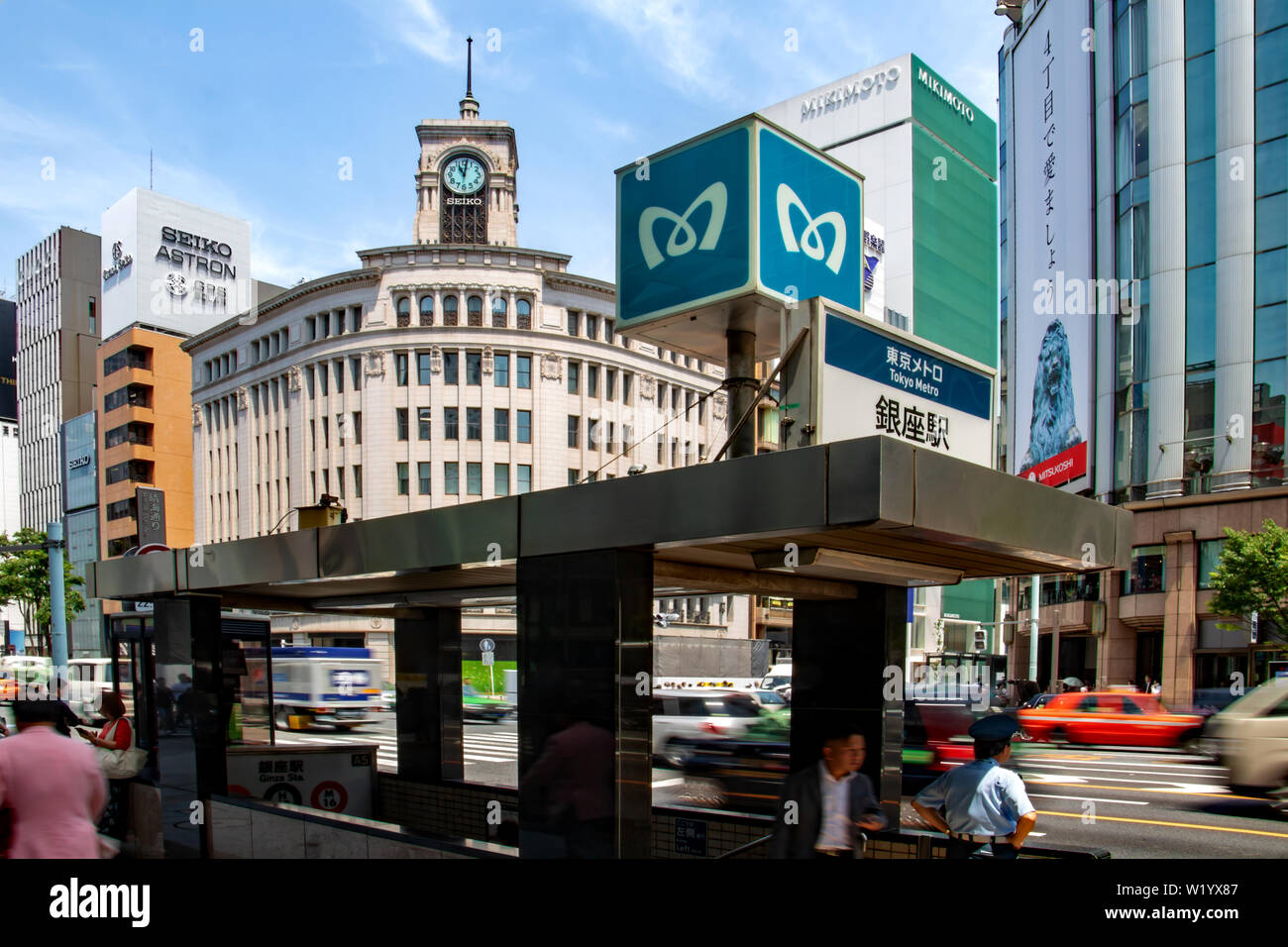 The entrance to the Ginza Metro Station at the Ginza Yonchome crossing in Tokyo, Japan has the Wako Department Store & Clock Tower as its backdrop Stock Photo