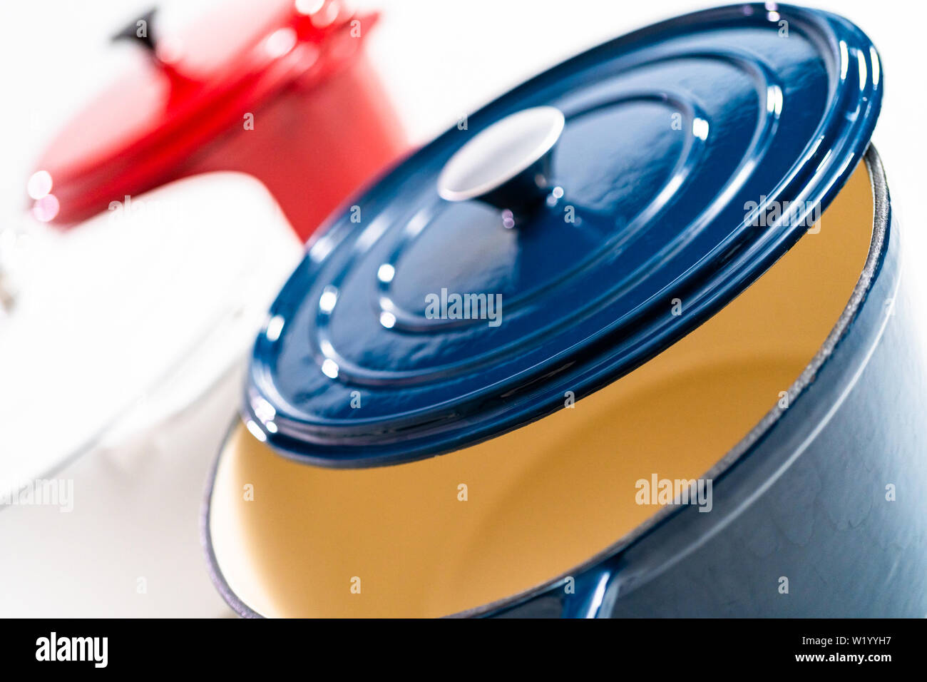 Red, white and blue enameled cast iron covered round dutch ovens on a whjite background. Stock Photo