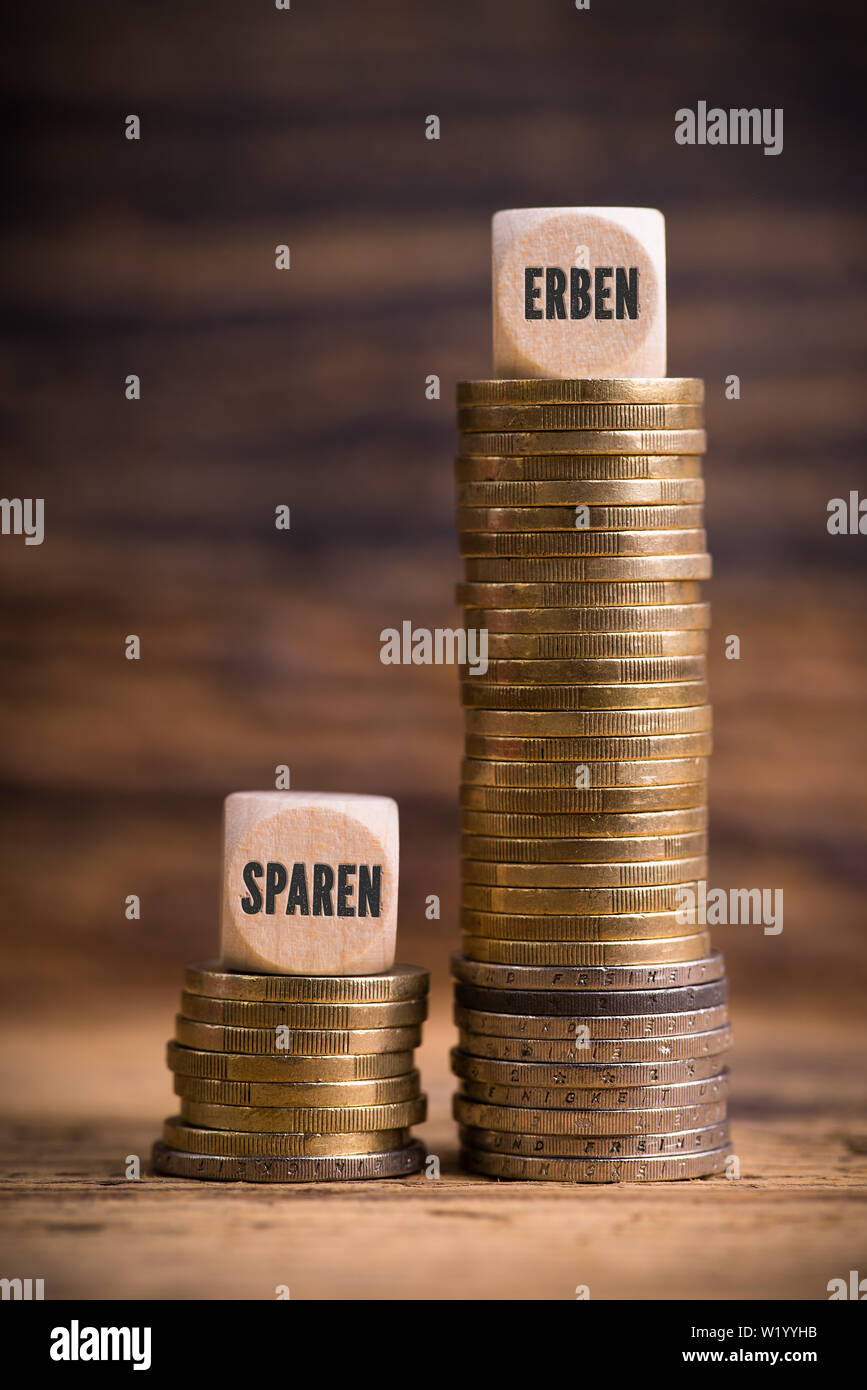 stacked coins showing unjust difference between saving money and inheriting it with the German words for 'save' and 'inherit' Stock Photo
