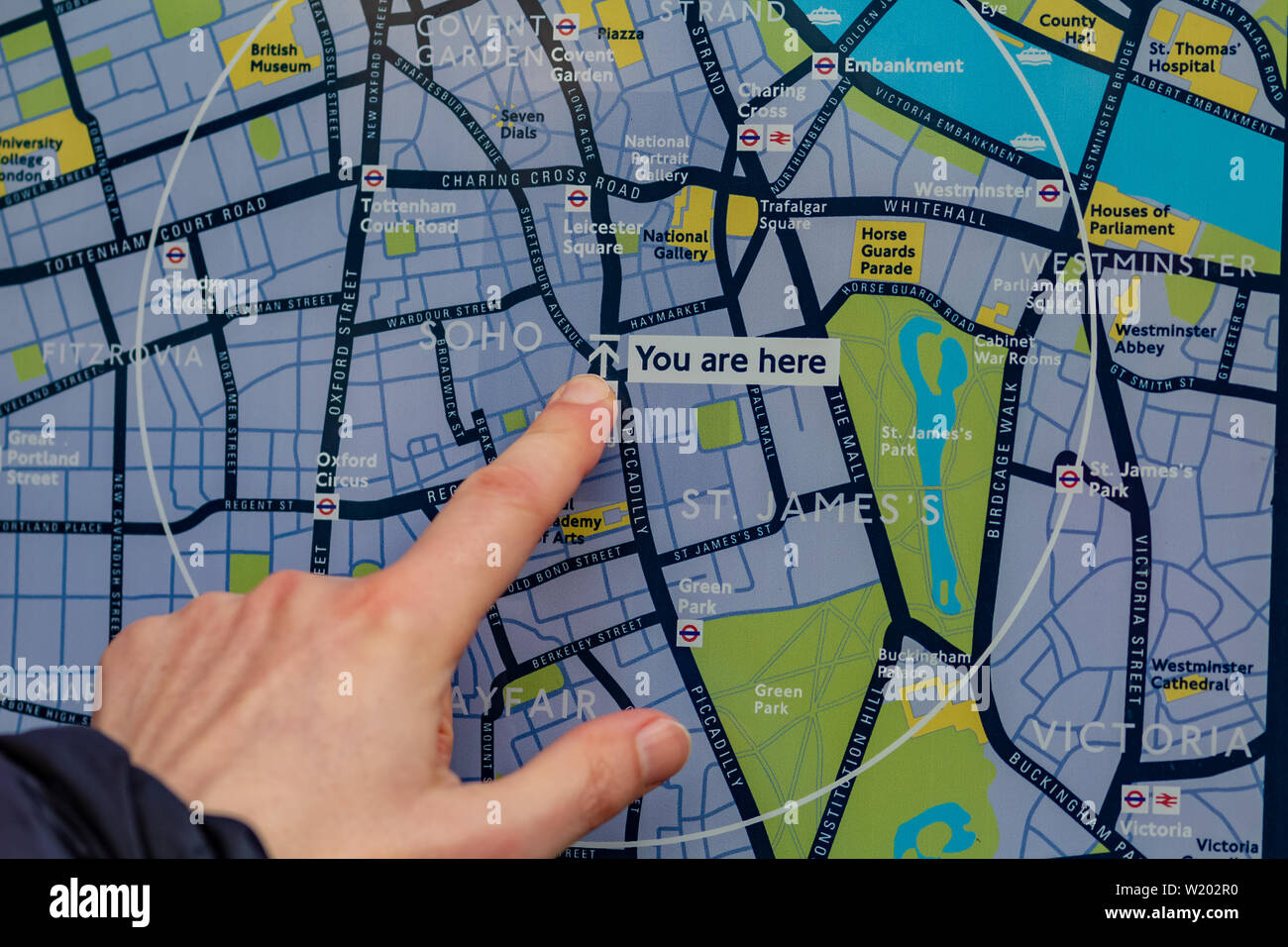 London, UK - 17, December 2018: The tourist looks at the map of London and shows by the finger where he is now. Stock Photo
