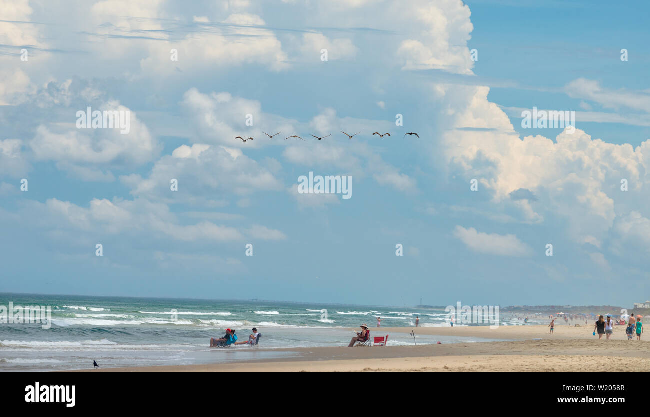 Pelicans Fly Overhead in Formation - North Carolina Outer Banks - Blue Skies and Clouds. Stock Photo