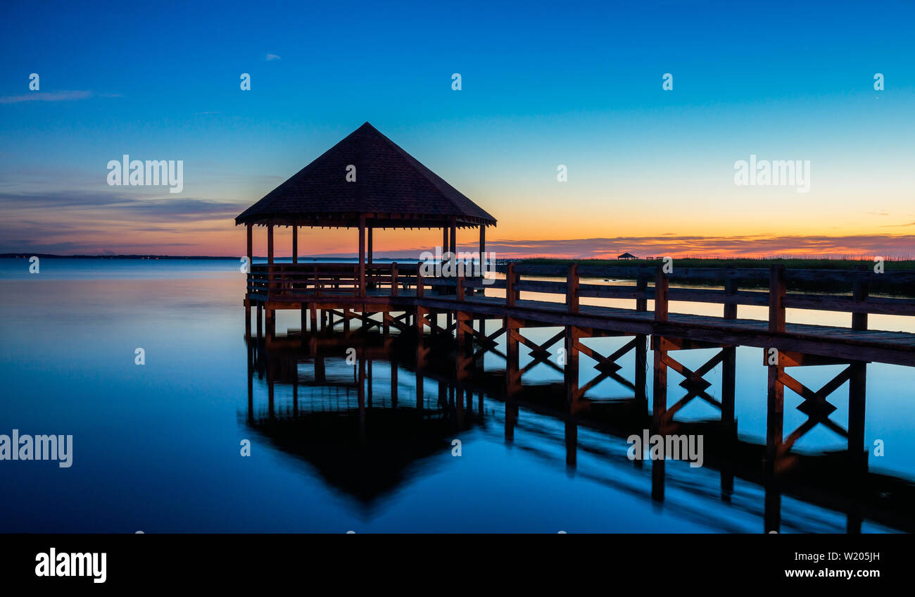 North Carolina Sound Tranquil Reflection Gazebo Boat Dock - Shortly after sunset on the sound. Soundside reflections of blue and orange. Stock Photo