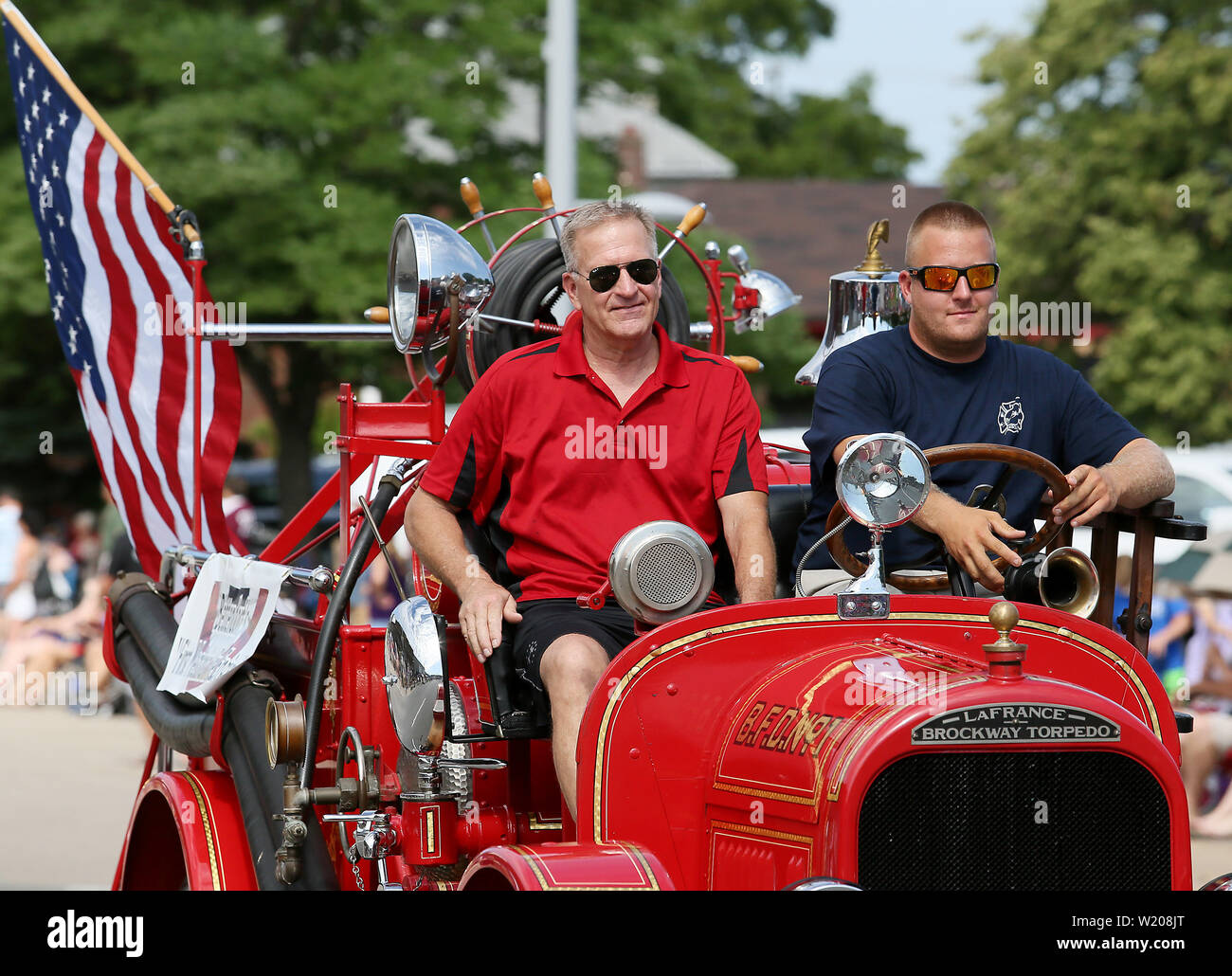 Bettendorf, Iowa, USA. 4th July, 2019. Austin, right and Rod Blunk with the Bettendorf Fire Department drive the departments first fire truck along State Street during the Fourth of July parade in Bettendorf, Iowa Thursday, July 04, 2019. The American LaFrance Brockway Torpedo, a 1922 model, came from Elmira, N.Y. It was purchased by the city of Bettendorf in 1924 for $6,000 and delivered by train in early November of that year. Credit: Kevin E. Schmidt/Quad-City Times/ZUMA Wire/Alamy Live News Stock Photo