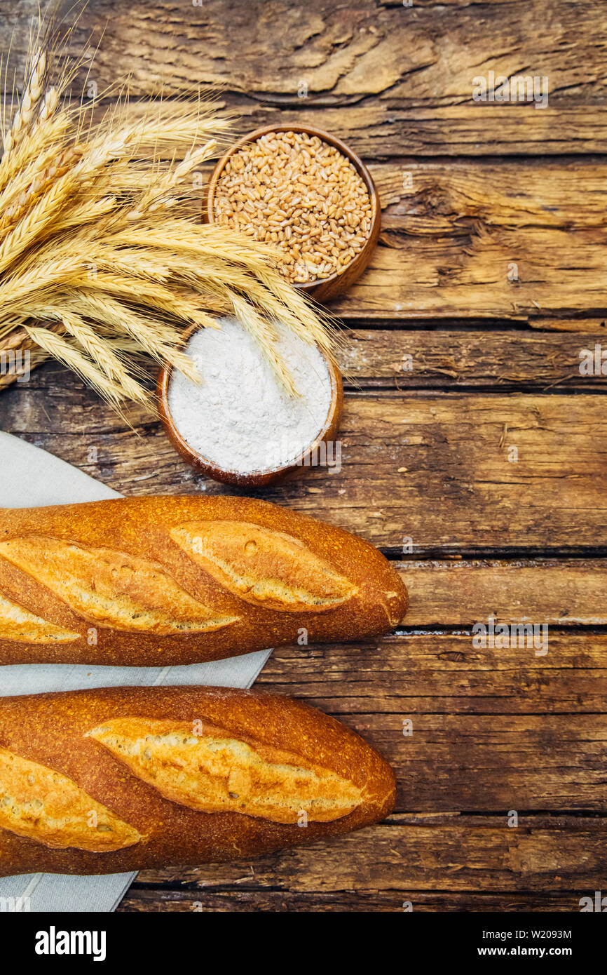 Assortment of baked fresh various rye, loaf or whole grain brown bread, wheat ear or spike and flour on wooden board table. Bakery concept image. Stock Photo