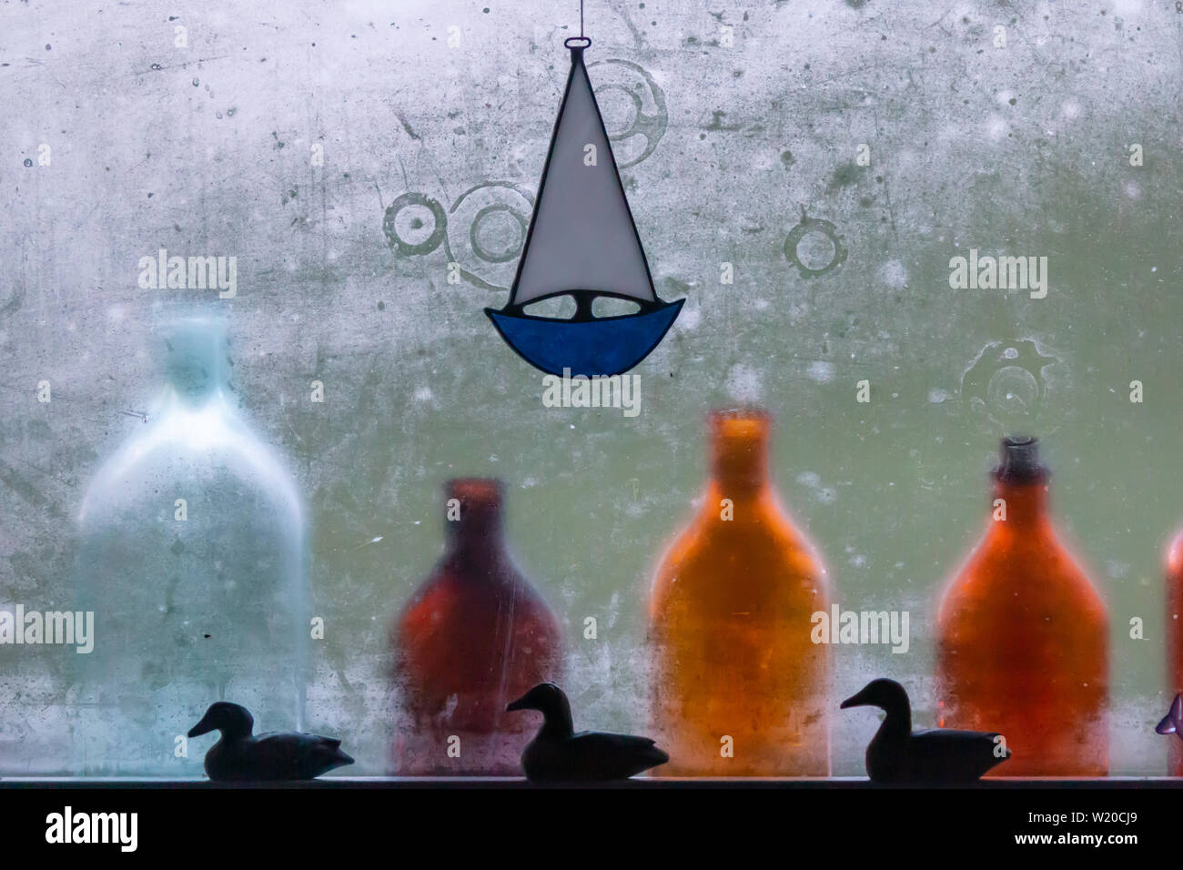 Colorful bottles lined up in front of a steamy glass window following a hot sauna in a cabin on the Finnish Archipelago. Stock Photo