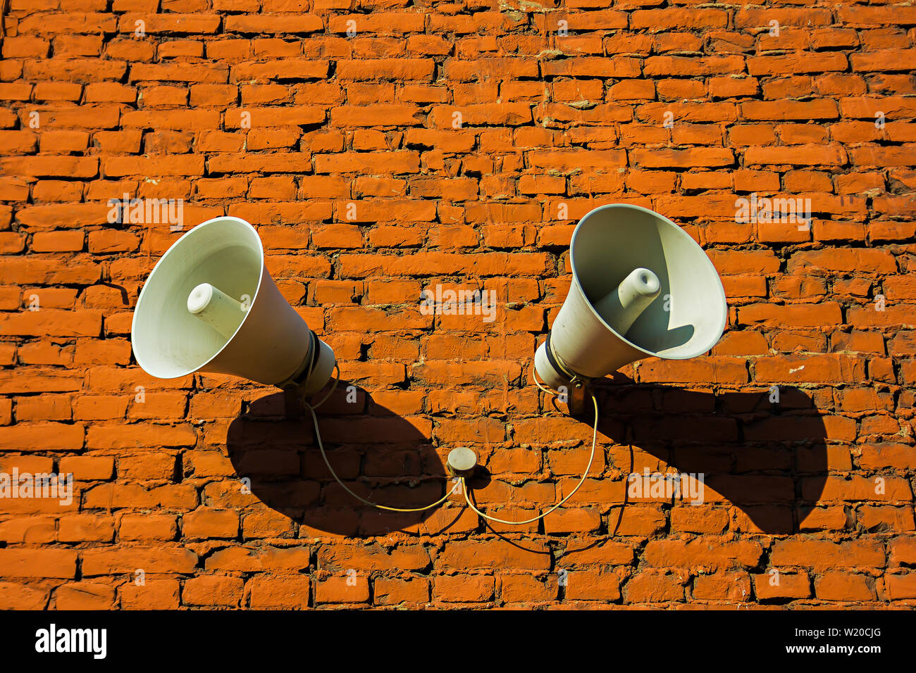 White loudspeakers attached to a red brick wall, background Stock Photo
