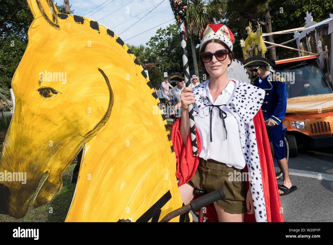 A woman dressed in costume rides a bicycle decorated as horses during the annual Independence Day golf cart and bicycle parade July 4, 2019 in Sullivan's Island, South Carolina. The tiny affluent Sea Island beach community across from Charleston holds an outsized golf cart parade featuring more than 75 decorated carts. Stock Photo