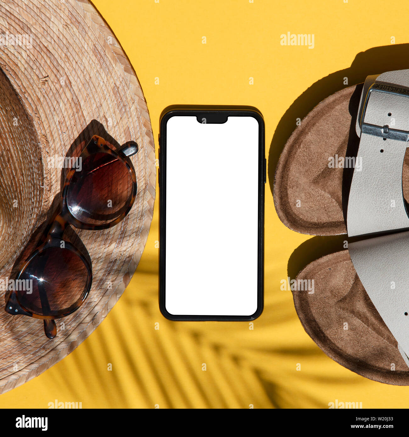 Summertime composition. Blank smartphone with summer accessories and palm shadow Stock Photo