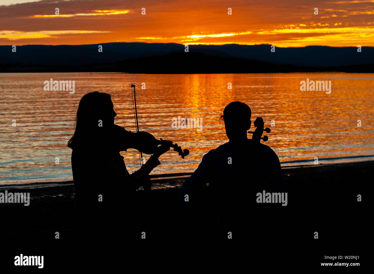 Bantry, West Cork, Ireland. 4th July, 2019. Bantry is hosting the West Cork Chamber Music Festival this week, which brings classical musicians from far and wide to play at the various concerts in the town. Violin player Kate Fleming and cellist Callum Owens, both from Cork, played as the sun went down this evening. Credit: Andy Gibson/Alamy Live News. Stock Photo