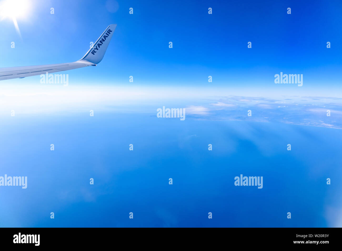 Valencia, Spain - March 8, 2019: Flaps of an Ryanair airplane seen from inside during a flight over the clouds of the sky. Stock Photo