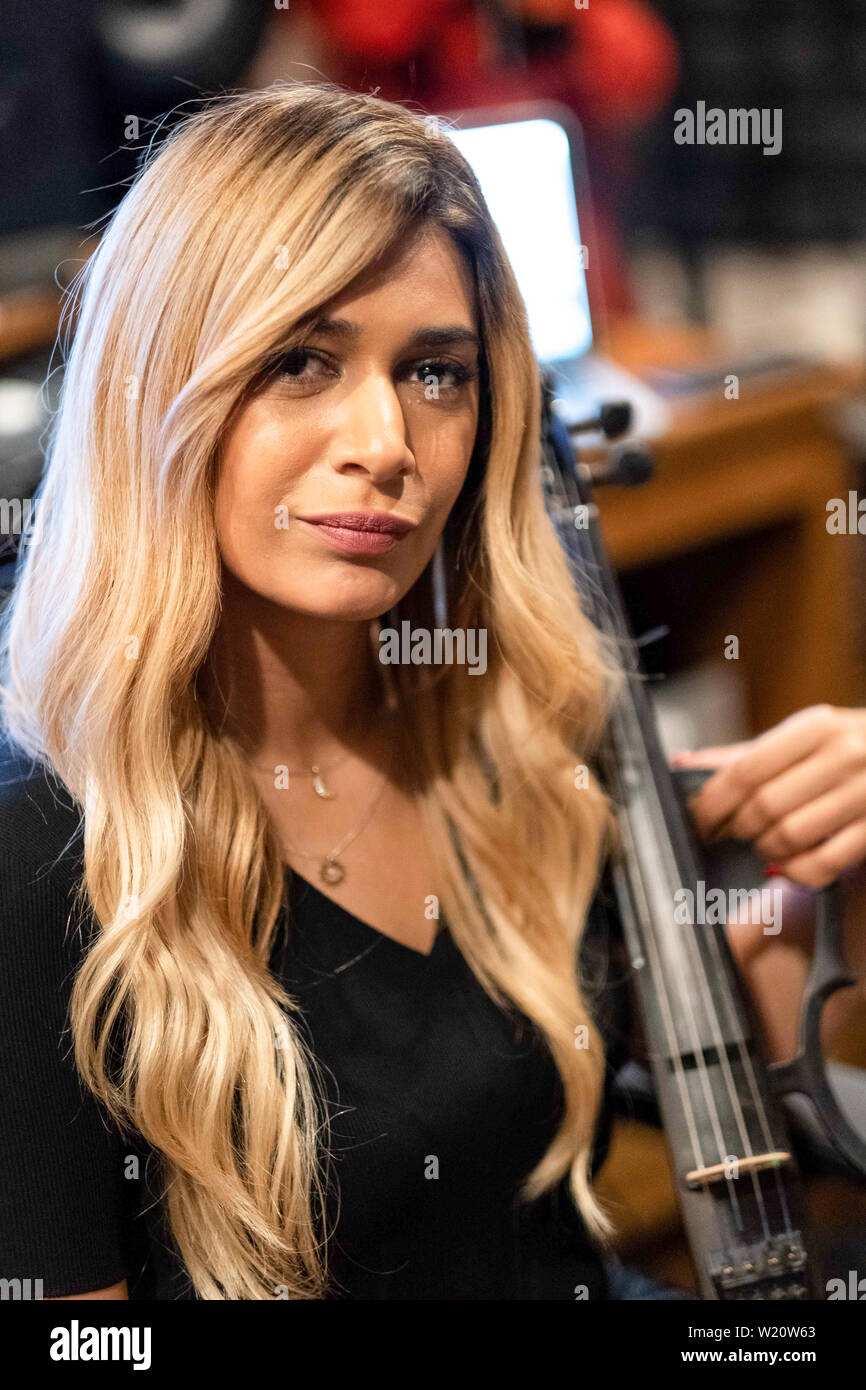 Music recording session in modern music studio. The equipment including violin, keyboards, sound speakers and keyboards. Blonde woman musician. Stock Photo