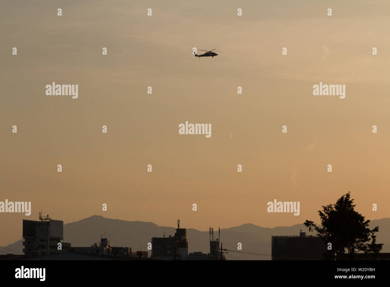 A Sikorsky SH-60 Seahawk helicopter in silhouette, flying at sunset out of Naval Air Facility Atsugi, airbase, Kanagawa, Japan. Stock Photo