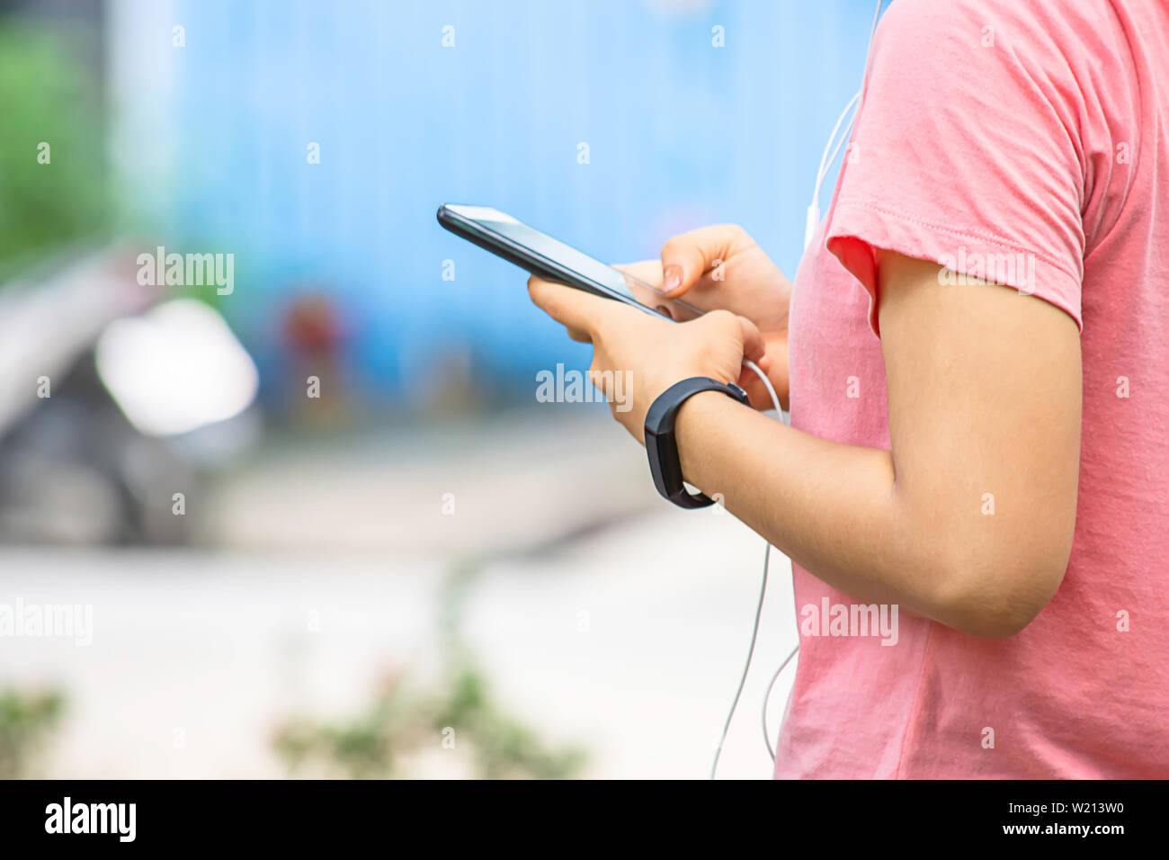 Hand of a woman wearing a watch and holding the phone plugged in headphones. Stock Photo