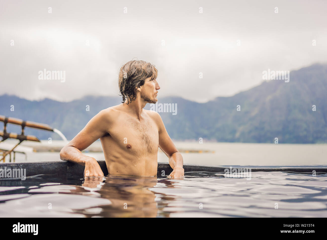 Geothermal spa. Man relaxing in hot spring pool. Young man enjoying bathing relaxed in a blue water lagoon, tourist attraction Stock Photo