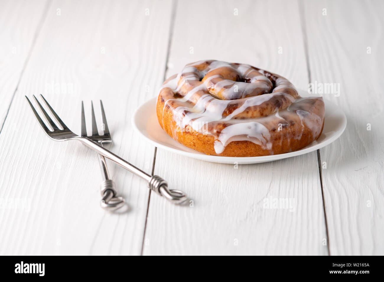 Large gourmet frosted cinnamon roll on white farmhouse table Stock ...