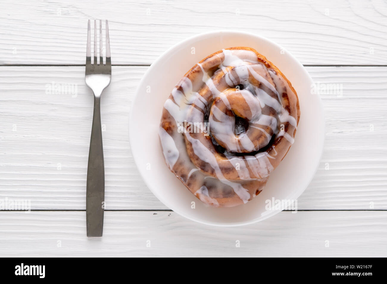 Large gourmet frosted cinnamon roll on white farmhouse table Stock ...