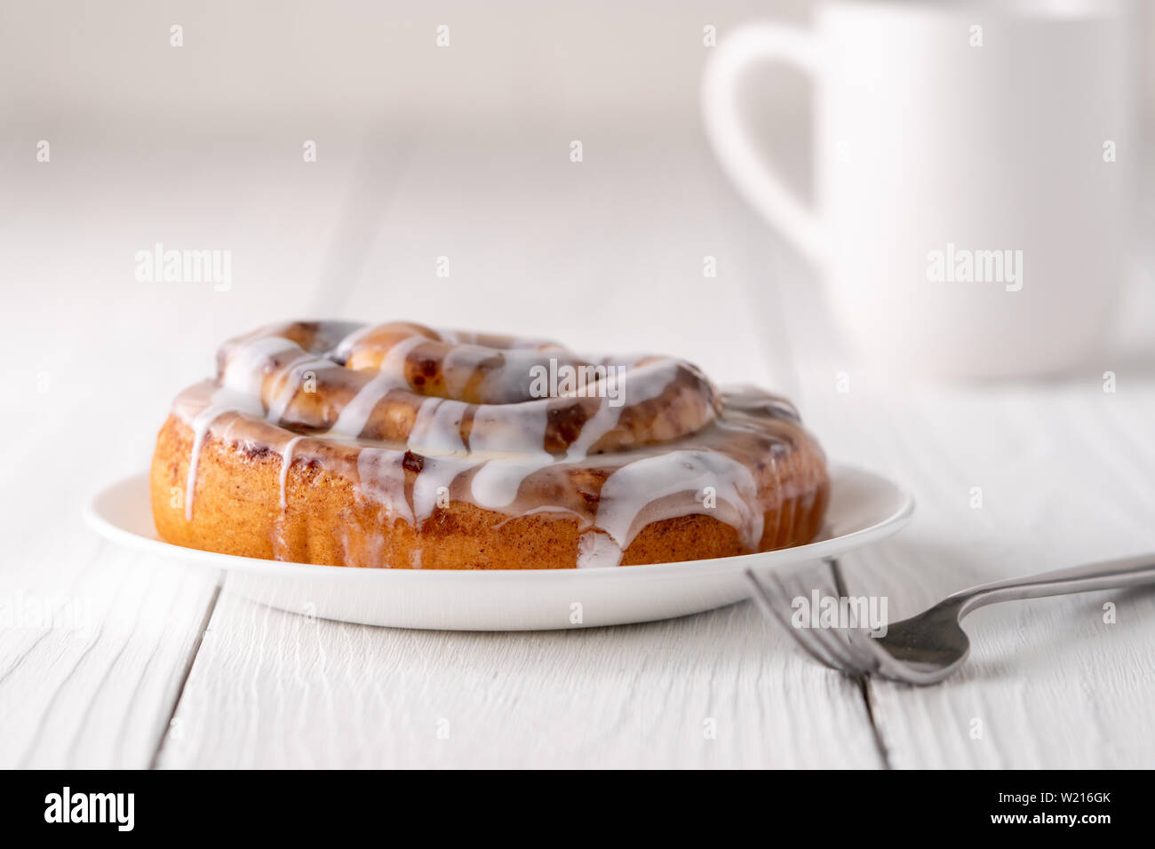 Large gourmet frosted cinnamon roll on white farmhouse table Stock ...