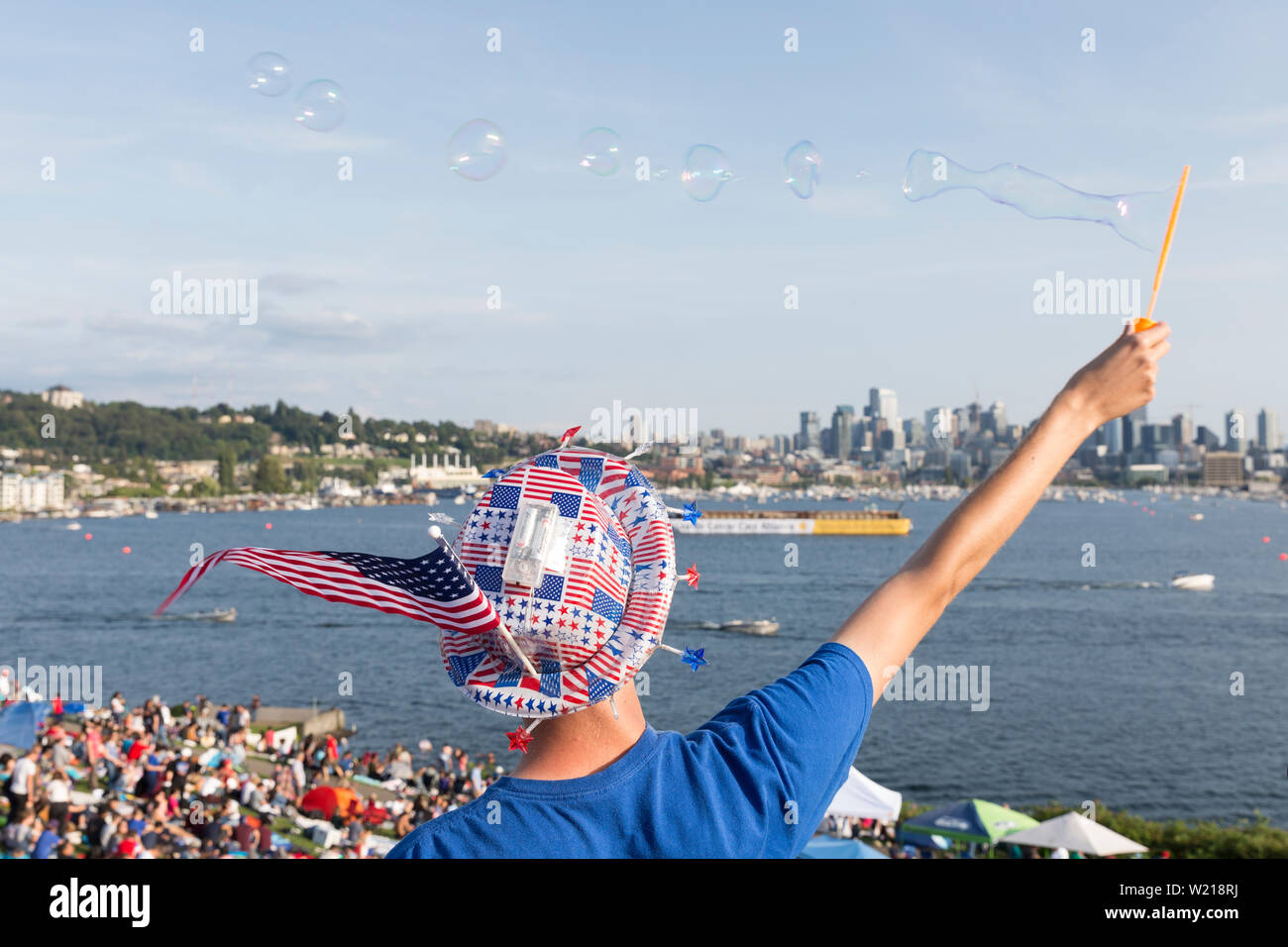 A man in patriotic American garb makes soap bubbles over the crowd at the Seafair Summer Fourth Independence Day Celebration at Gas Works Park on July 4, 2019 in Seattle, Washington. Stock Photo