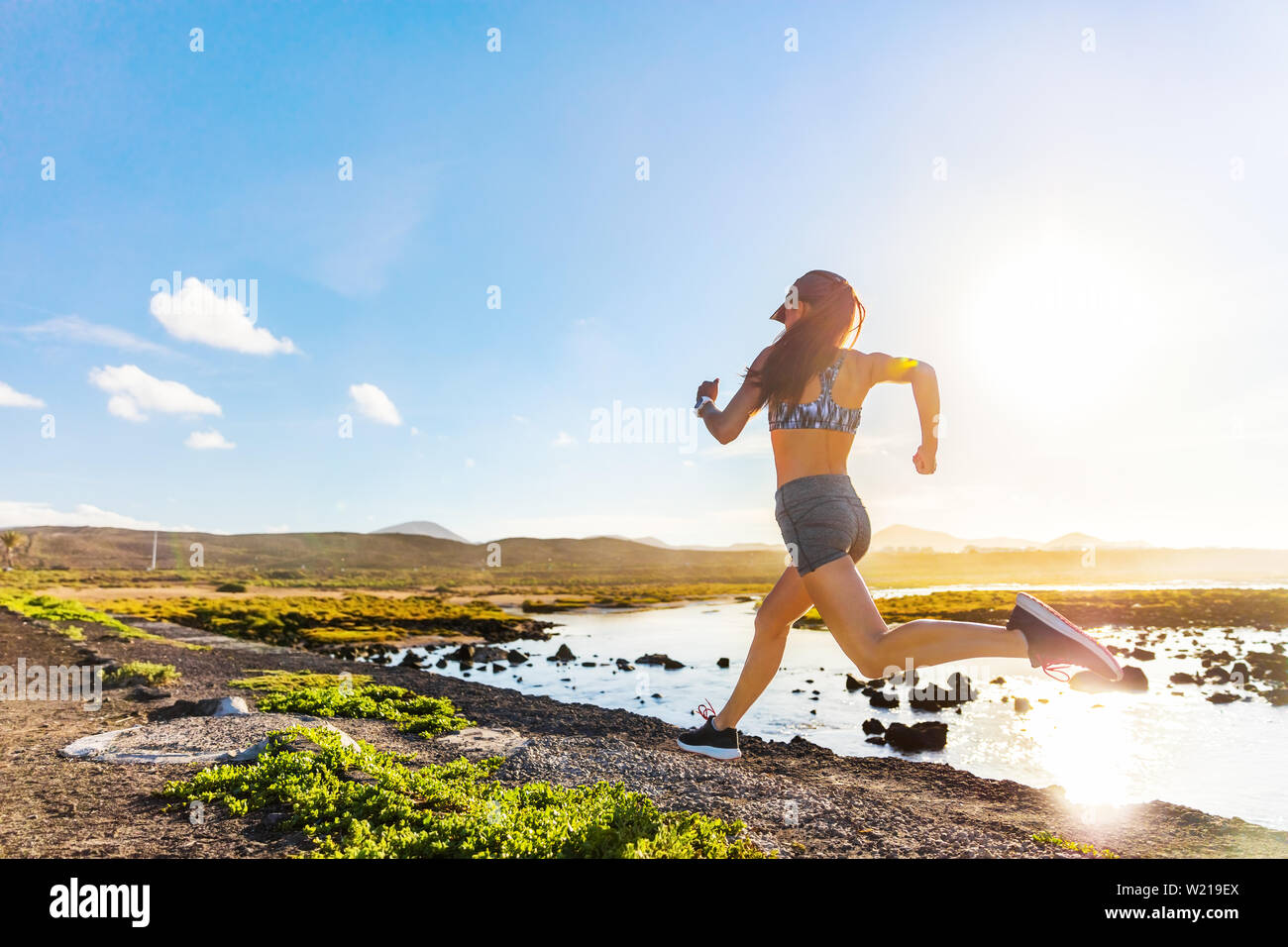 Athlete Runner Trail Running On Summer Trail Beach Active Morning Jogging Motivation Woman Sprinting With Energy And Motion In Outdoors Nature Training Cardio Race In Shorts And Sports Bra Shoes Stock Photo