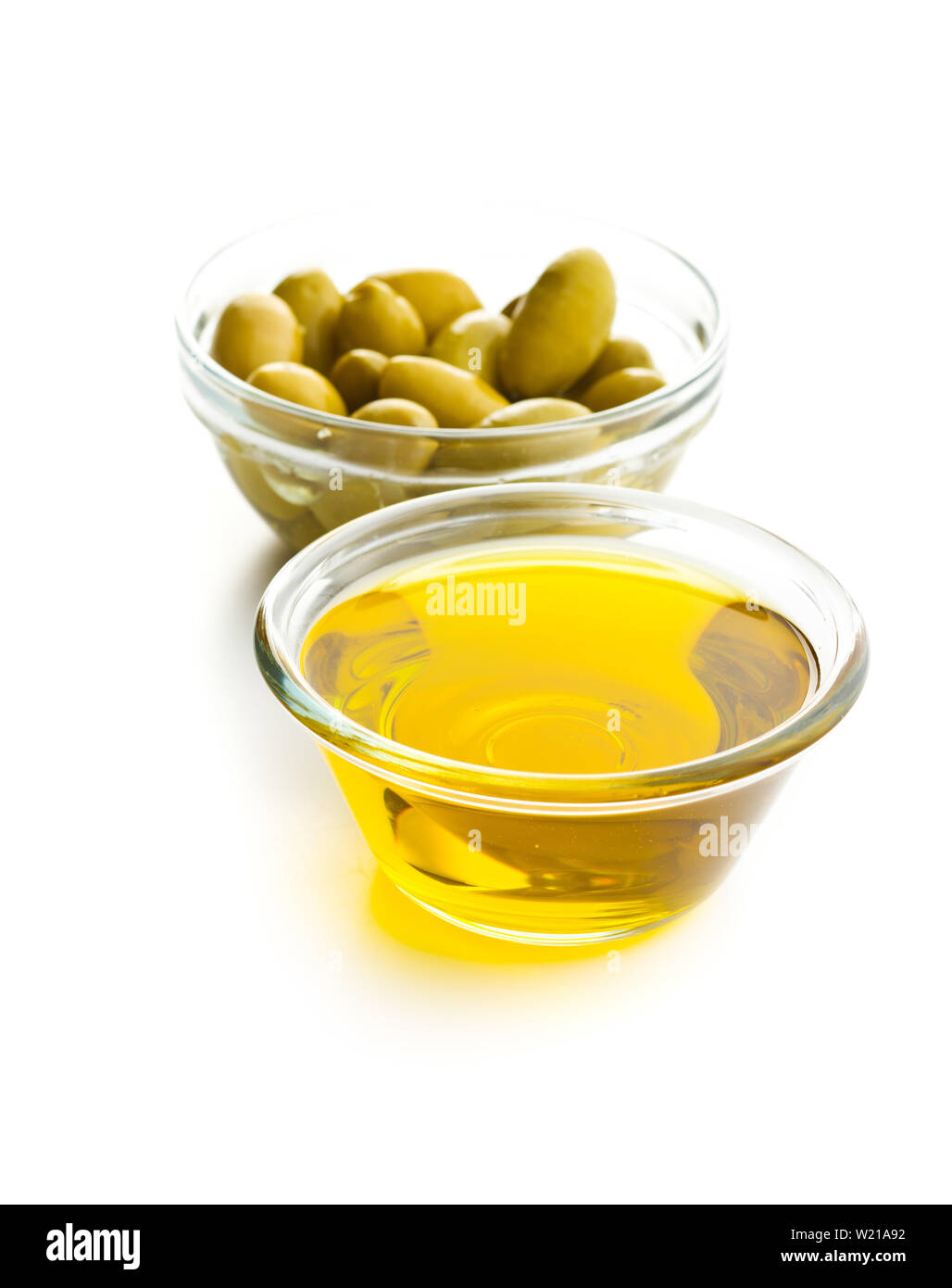 Green olives and olive oil in glass bowl isolated on white background ...