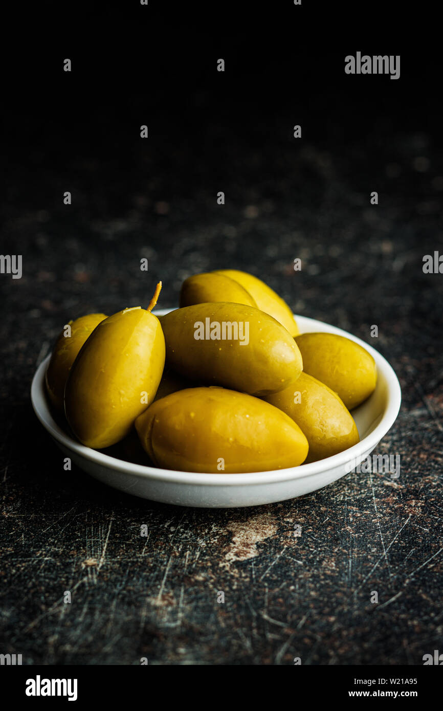 Green olives on old kitchen table. Stock Photo
