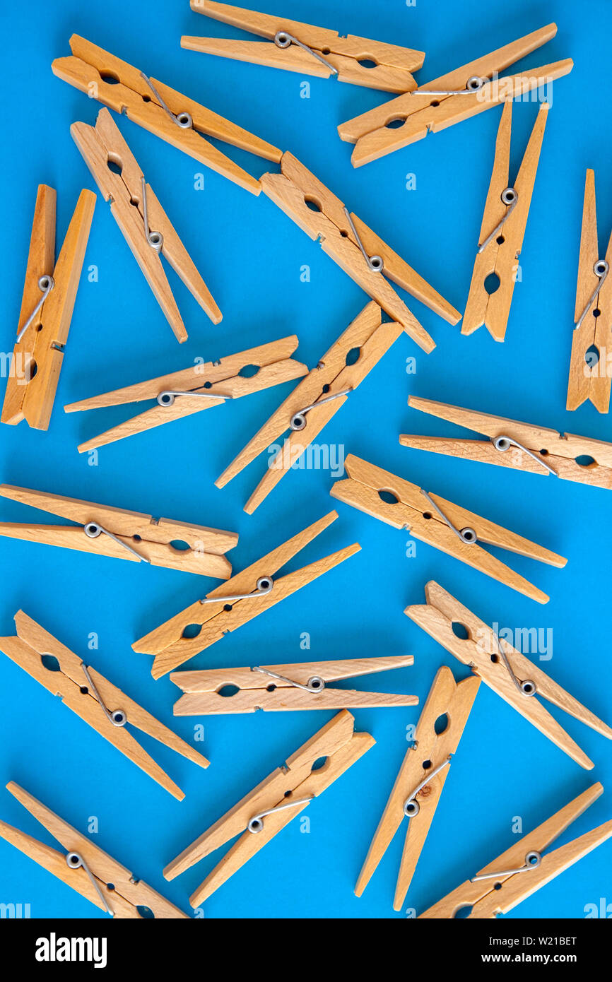 Wooden yellow clothespins are scattered on a cyanblue background
