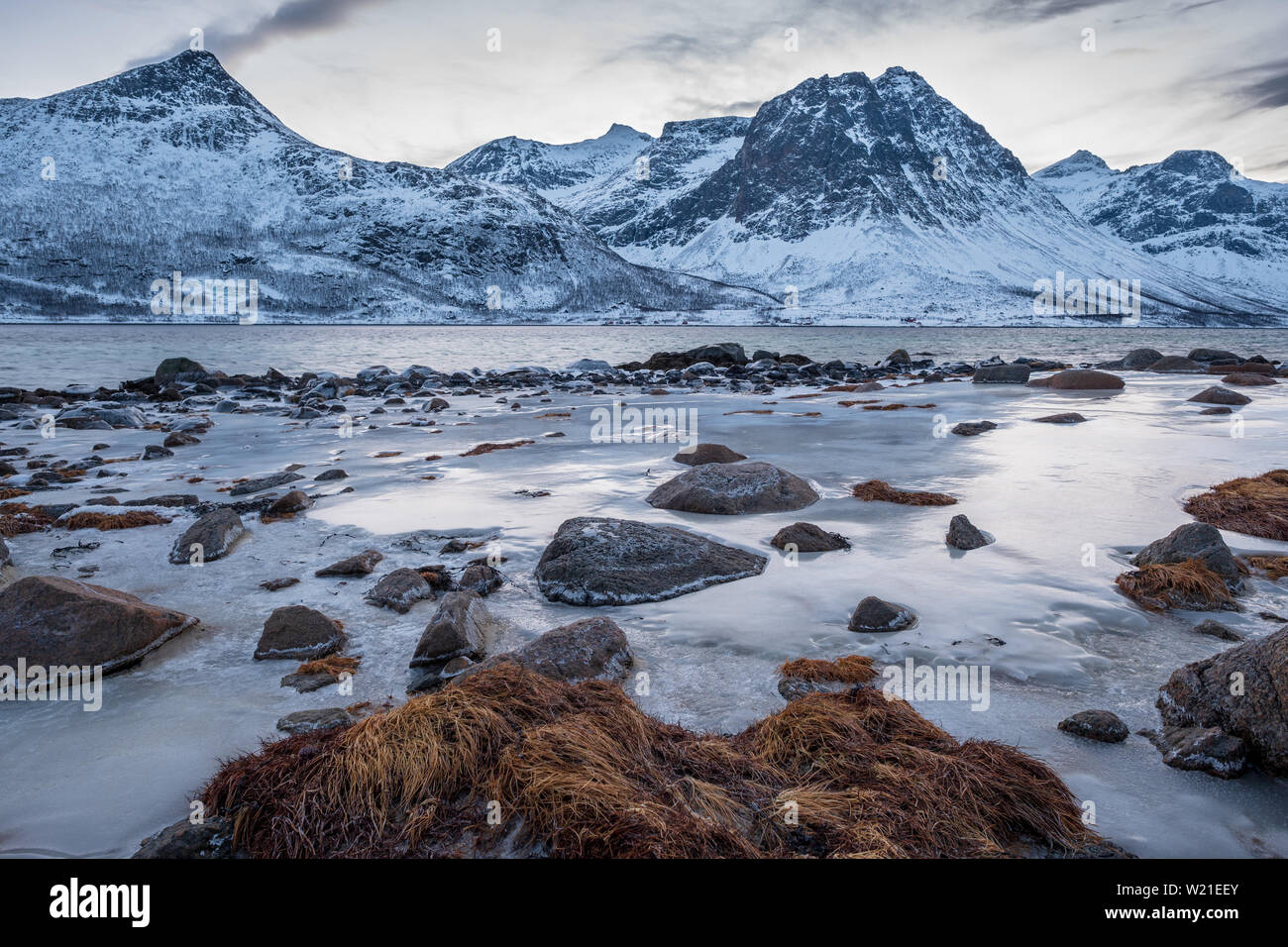 Nordic landscape of a fjord with stones, mountains, ice, Tromsø  Kvaløya Norway Stock Photo