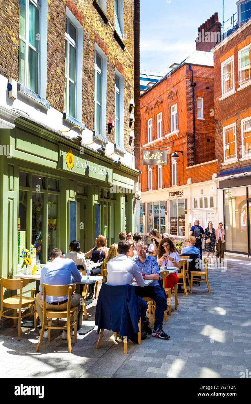 People eating lunch al fresco at the Sunflower Kitchen cafe, Pollen Street, Mayfair, London, UK Stock Photo