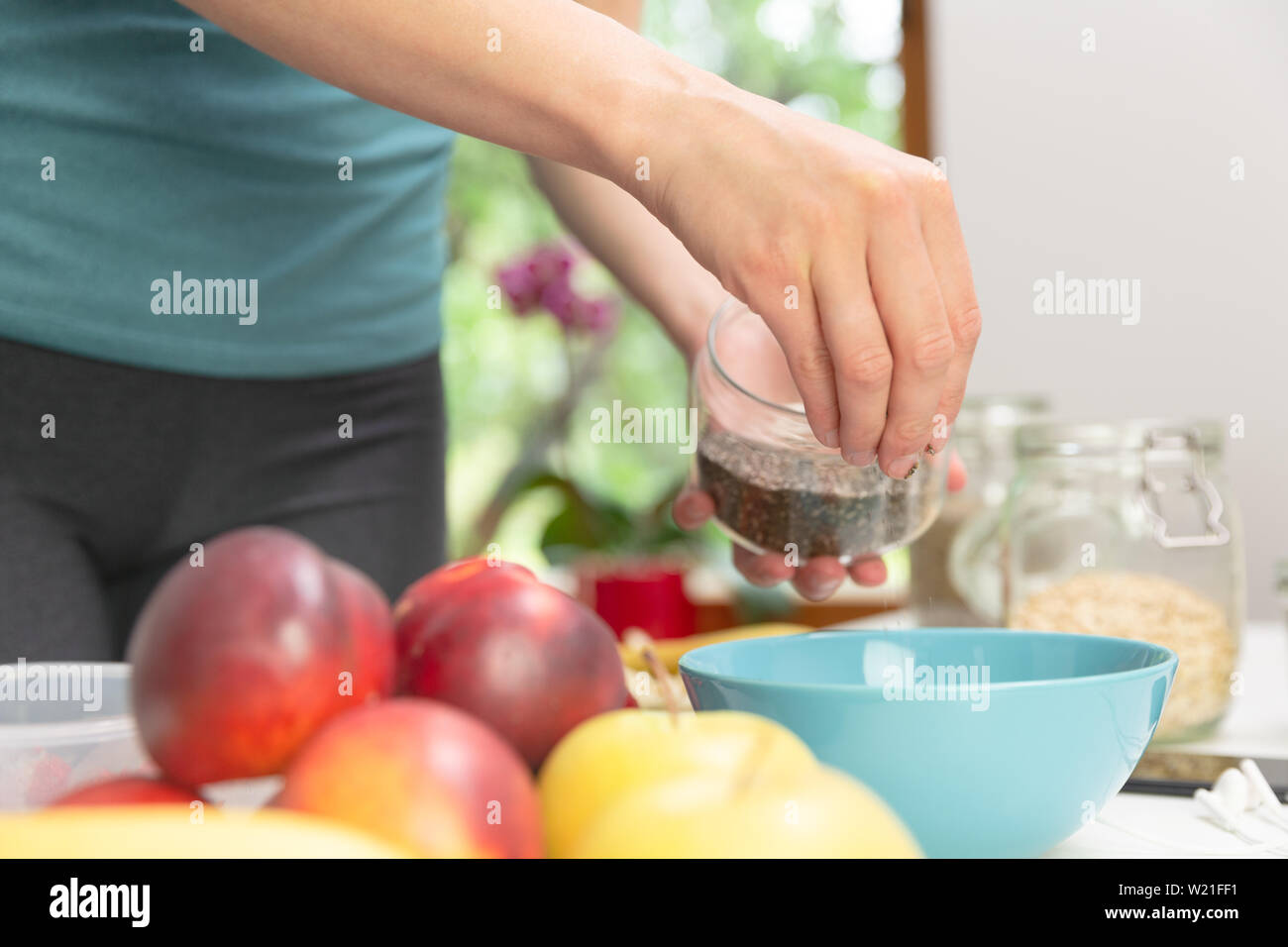 Woman preparing healthy fitness breakfast: oatmeal with bananas, strawberries and chia seeds Stock Photo