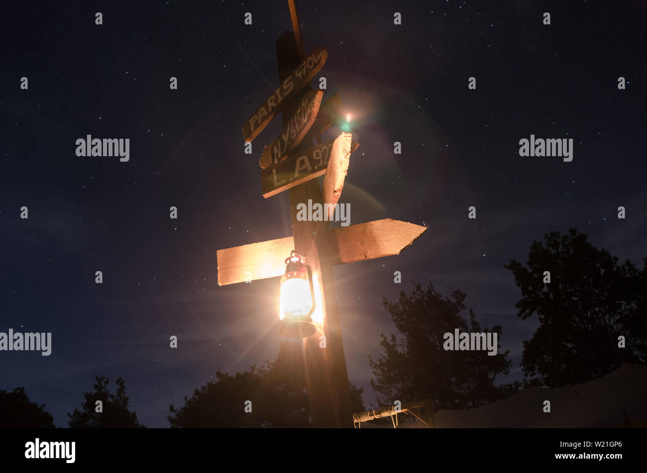 Wegweiser mit Öllampe vor Sternenhimmel Stock Photo