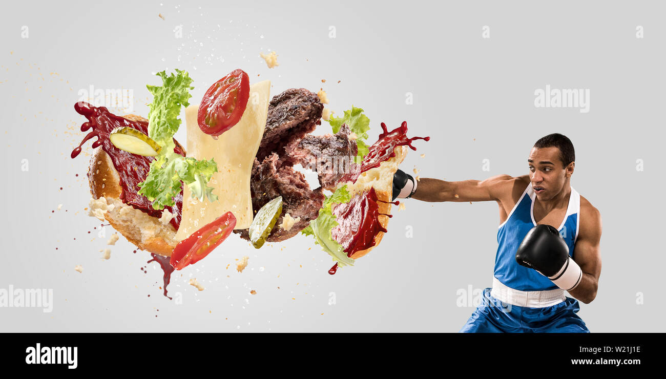 Fight the fast food. Burger's crashing by the boxer isolated on white
