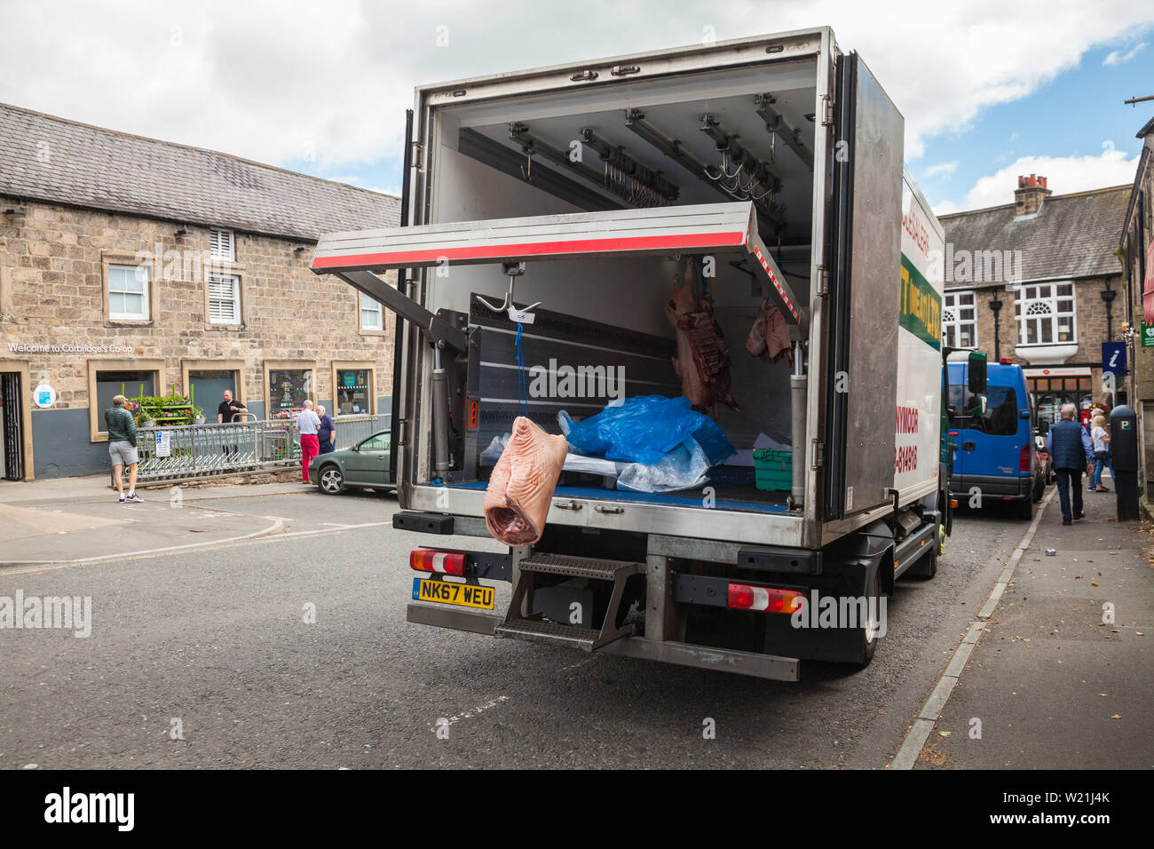 A meat supplier delivering to a butchers shop in Corbridge,England,UK. Meat hanging from a hook at the back of the van Stock Photo